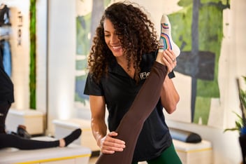 female stretch therapist stretching a client's leg in an iFlex studio