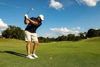 male golfer on golf course mid swing